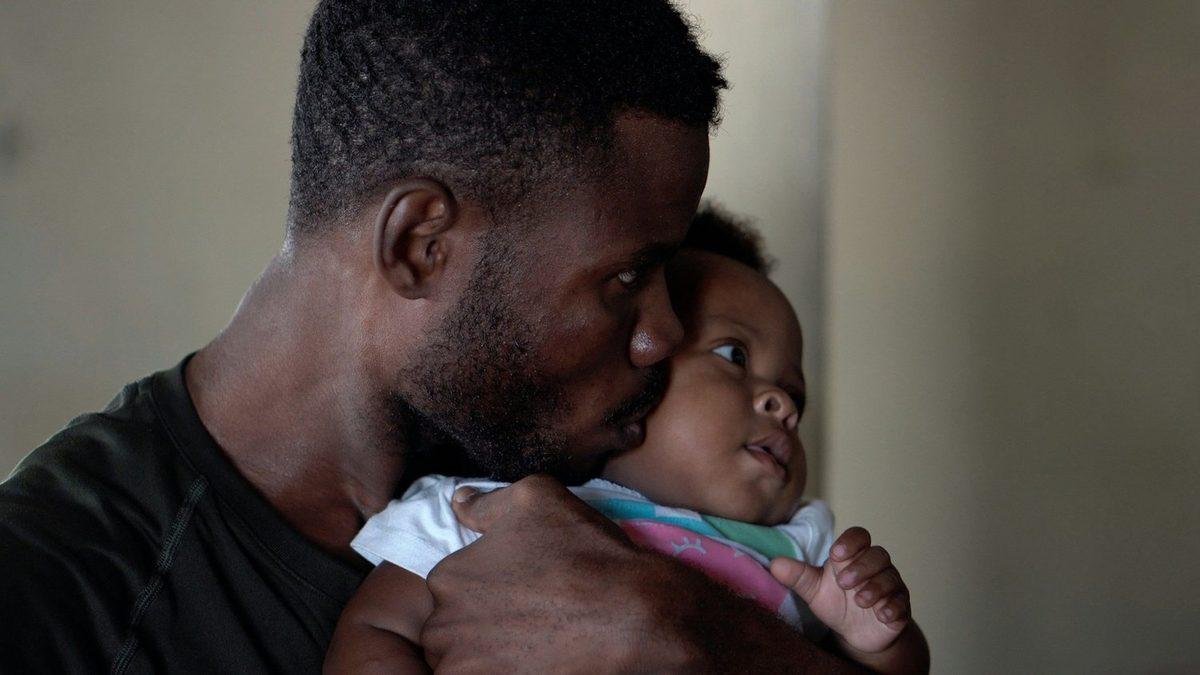 A father holding and kissing his infant child
