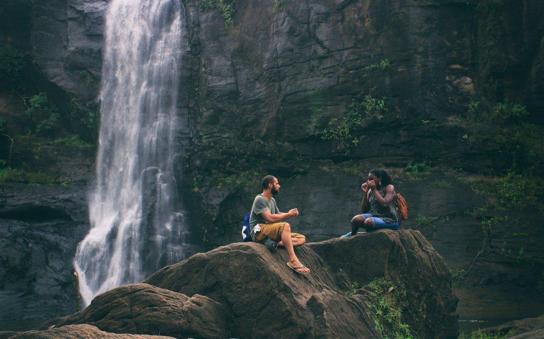 A family sitting together beside a waterfall on a hike